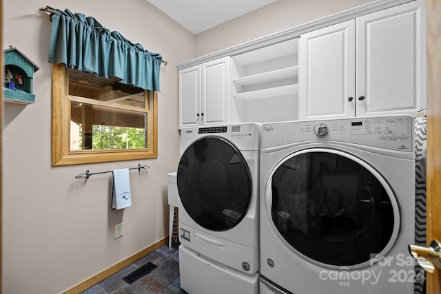 clothes washing area featuring cabinets and washer and dryer