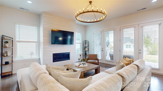 living room featuring a fireplace, french doors, dark hardwood / wood-style flooring, and a notable chandelier