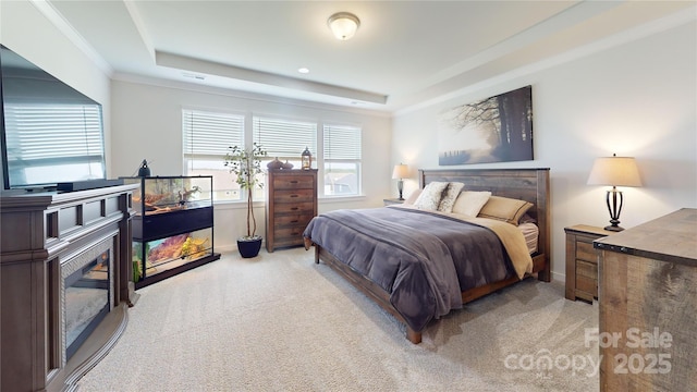 carpeted bedroom with a tray ceiling and ornamental molding