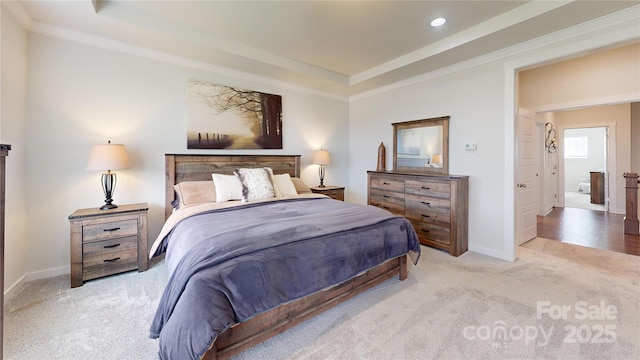 bedroom with a tray ceiling, light colored carpet, and ornamental molding