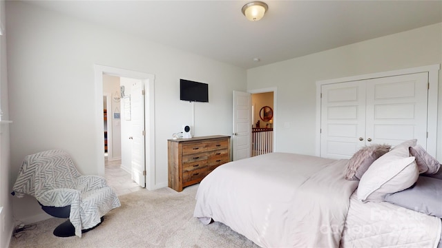 bedroom featuring ensuite bathroom, a closet, and light colored carpet