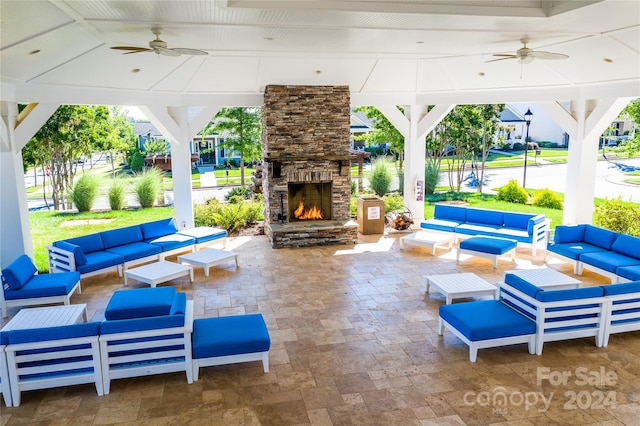 view of patio with ceiling fan and an outdoor living space with a fireplace