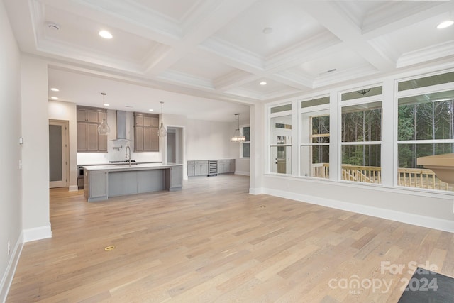 unfurnished living room featuring coffered ceiling, light hardwood / wood-style flooring, beam ceiling, and sink