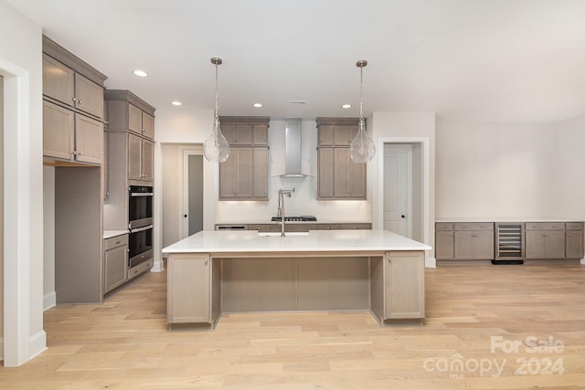 kitchen featuring a large island, wall chimney range hood, and light hardwood / wood-style flooring