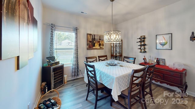 dining space with a notable chandelier, dark hardwood / wood-style flooring, and beverage cooler