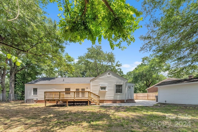 rear view of property featuring a deck, a lawn, and a patio