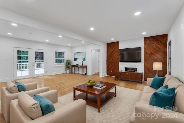 living room with french doors, light wood-type flooring, and a fireplace