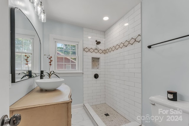 bathroom featuring vanity, toilet, and a tile shower