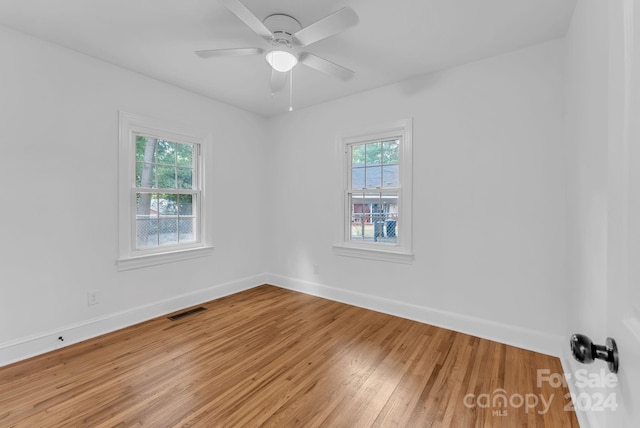 empty room featuring wood-type flooring, ceiling fan, and a wealth of natural light