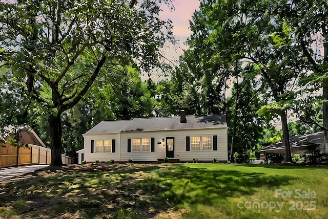 ranch-style house featuring a yard and fence