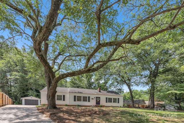 single story home with a garage, an outdoor structure, a chimney, and fence