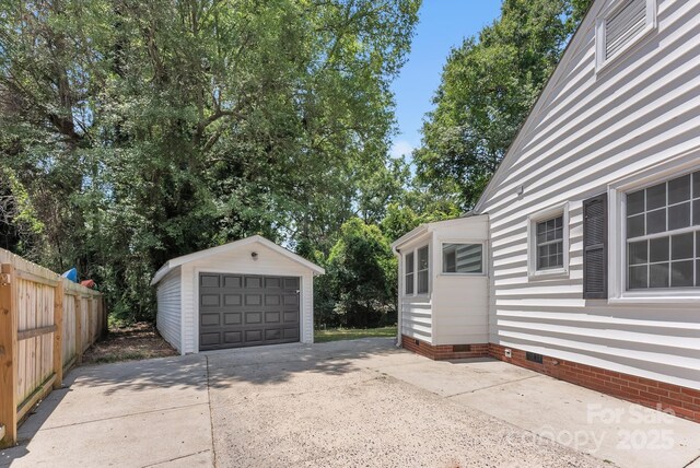 detached garage with concrete driveway and fence