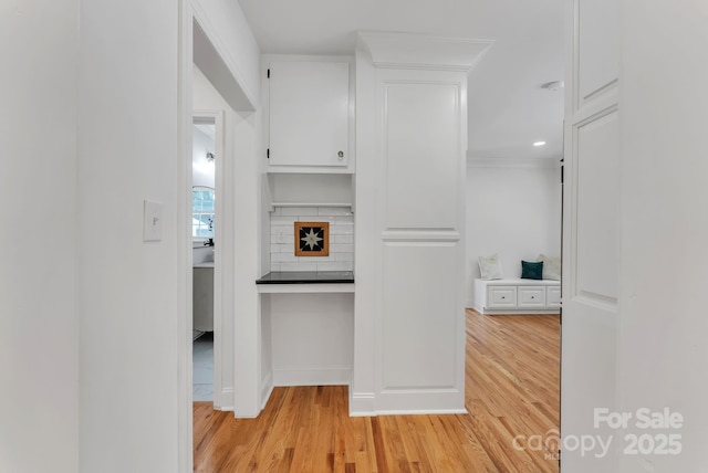 interior space with dark countertops, decorative backsplash, white cabinets, and light wood-style floors