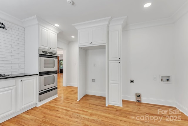 kitchen featuring dark countertops, light wood-style flooring, ornamental molding, stainless steel double oven, and a warming drawer