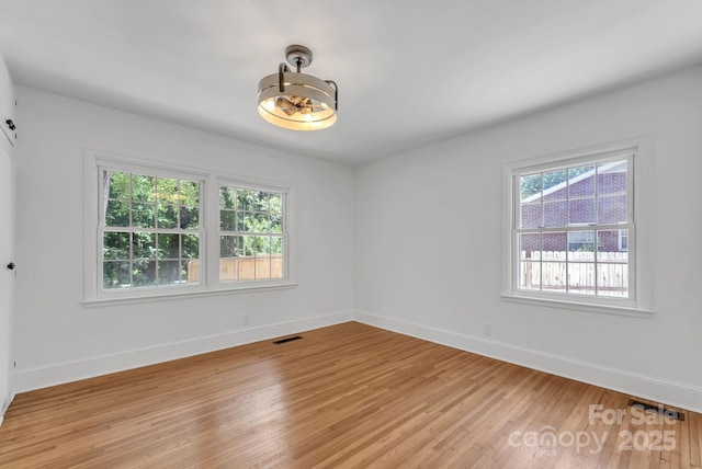 unfurnished room with a healthy amount of sunlight, light wood-style floors, and visible vents