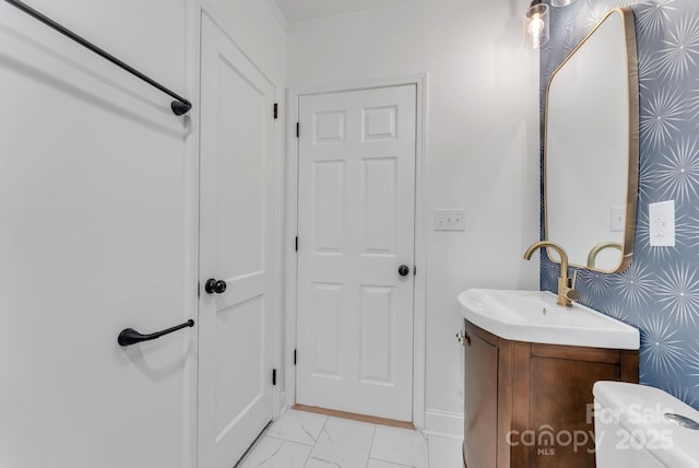 bathroom with wallpapered walls, baseboards, ornamental molding, marble finish floor, and vanity