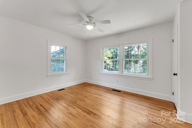 spare room featuring a ceiling fan, wood finished floors, visible vents, and baseboards