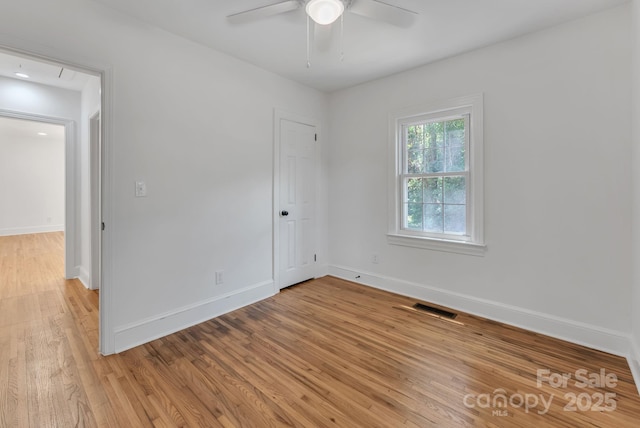 spare room with a ceiling fan, visible vents, light wood-style flooring, and baseboards