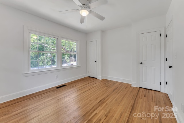 spare room featuring visible vents, ceiling fan, light wood-style flooring, and baseboards