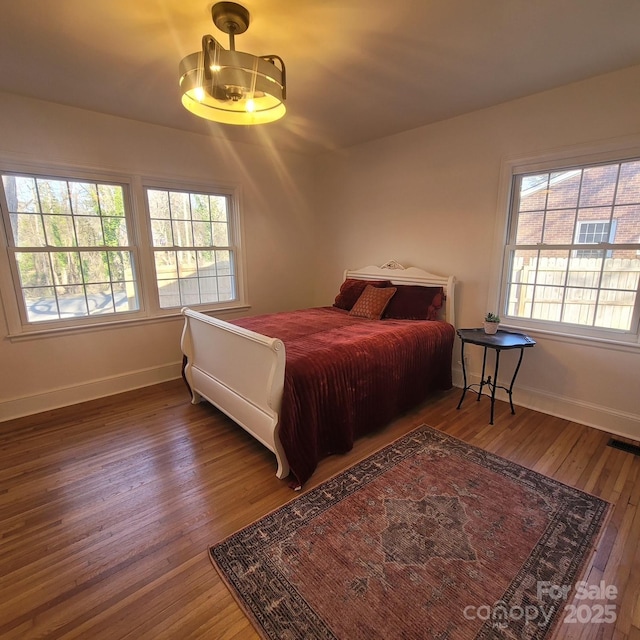 bedroom featuring hardwood / wood-style flooring, visible vents, baseboards, and an inviting chandelier