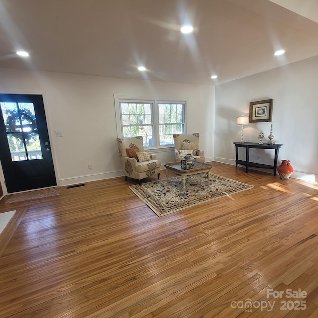 living area with baseboards, wood finished floors, visible vents, and recessed lighting