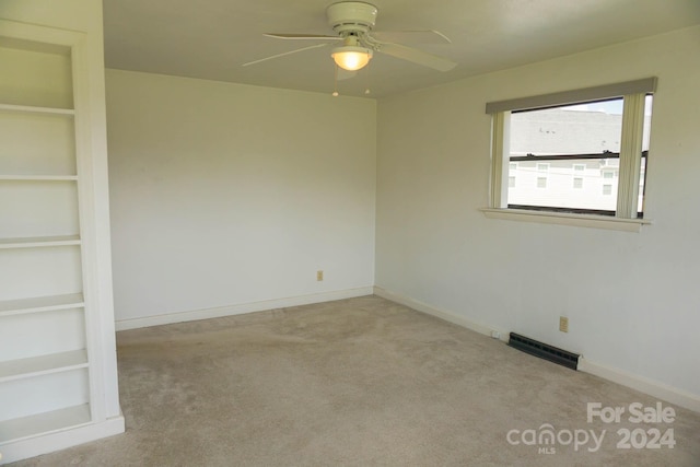 carpeted empty room with built in shelves and ceiling fan