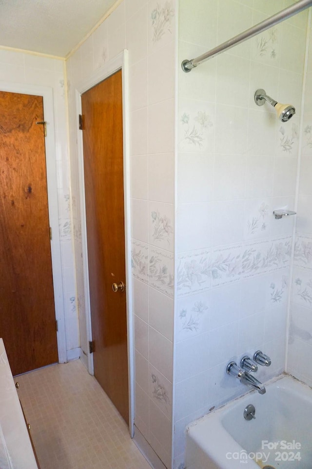 bathroom featuring tiled shower / bath combo and tile walls