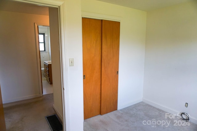 unfurnished bedroom with light colored carpet and a closet