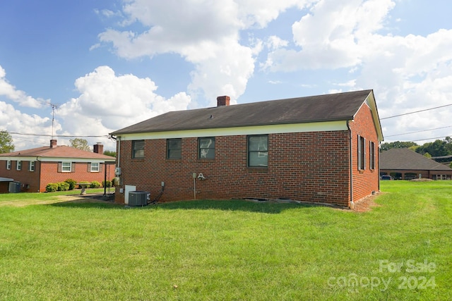 rear view of property with a lawn and central air condition unit