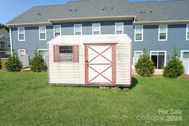 back of property featuring a lawn and a storage shed