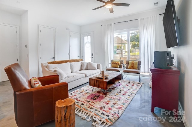 living room featuring ceiling fan and concrete flooring