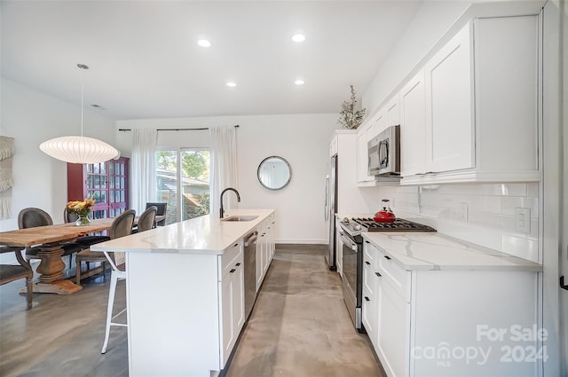 kitchen featuring light stone counters, hanging light fixtures, backsplash, white cabinetry, and stainless steel appliances