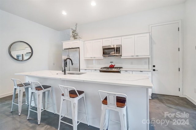 kitchen featuring concrete floors, a kitchen island with sink, stainless steel appliances, and white cabinets