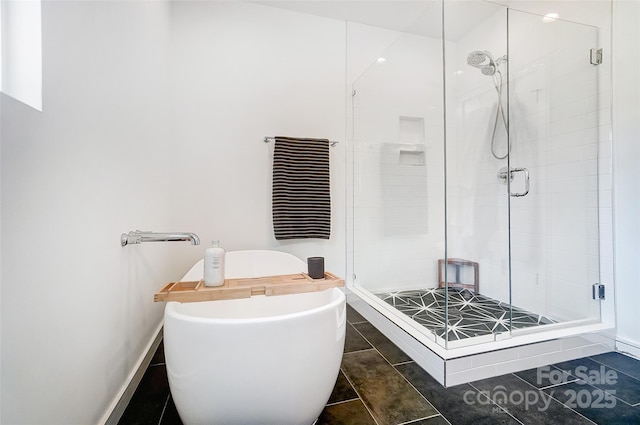 full bathroom featuring a stall shower, a freestanding tub, tile patterned flooring, and baseboards