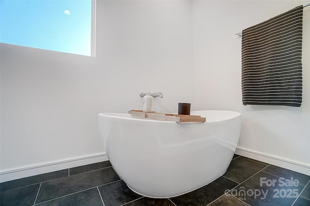 bathroom featuring a baseboard heating unit, a freestanding tub, tile patterned flooring, and baseboards