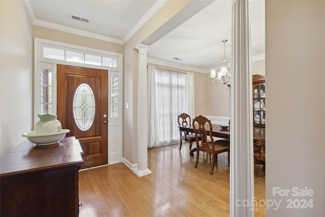 foyer with ornamental molding, light hardwood / wood-style flooring, a chandelier, and ornate columns