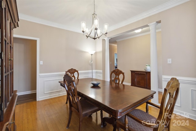 dining room with ornamental molding, a notable chandelier, light wood-type flooring, and ornate columns