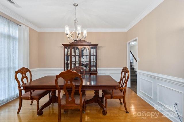 dining area featuring light hardwood / wood-style flooring, a notable chandelier, and ornamental molding