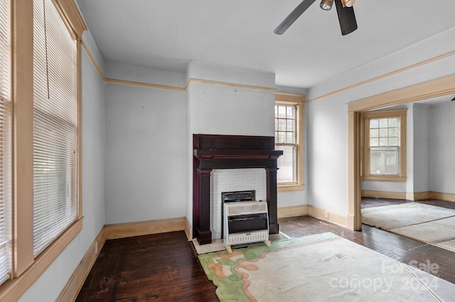 unfurnished living room with heating unit, wood-type flooring, a fireplace, and ceiling fan