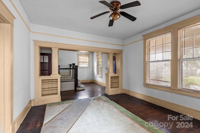 interior space with dark hardwood / wood-style flooring, ceiling fan, and ornate columns