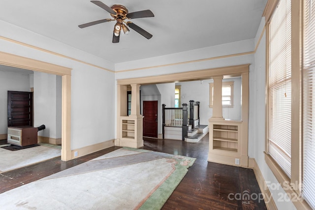 workout room with ceiling fan, dark wood-type flooring, and ornate columns