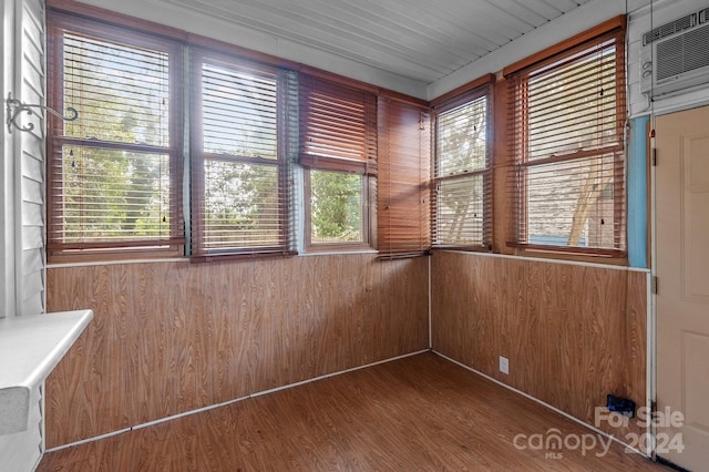 empty room featuring wooden walls, hardwood / wood-style floors, and a wall unit AC