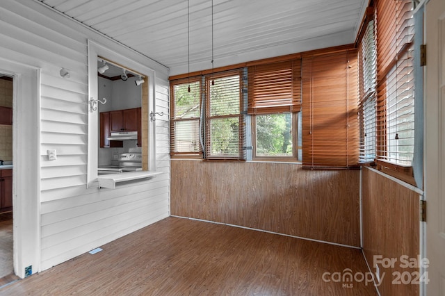 unfurnished room featuring wood-type flooring and wood walls