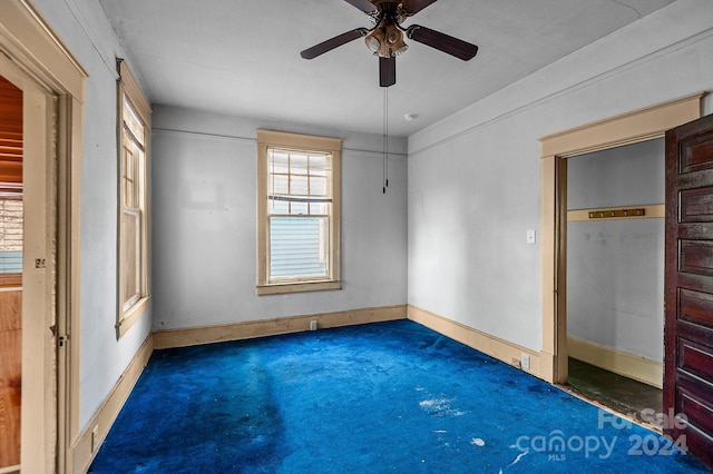 unfurnished bedroom with dark carpet and ceiling fan