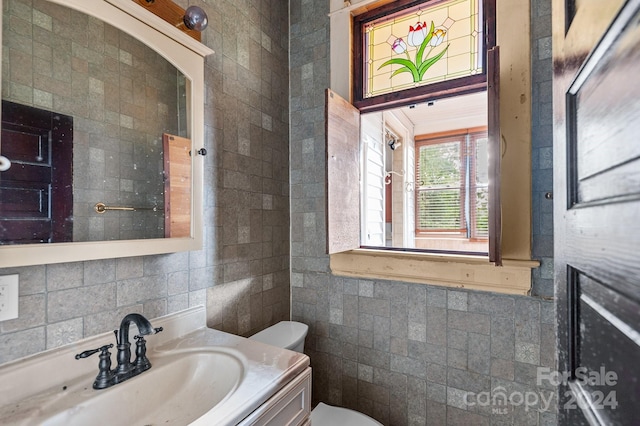 bathroom featuring vanity, tile walls, and toilet