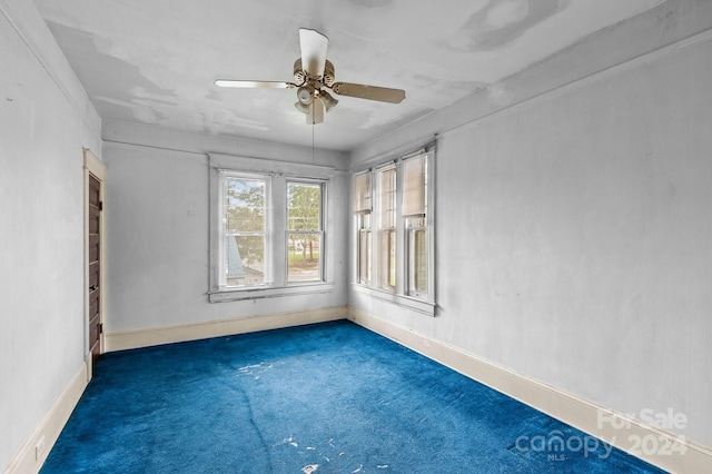 spare room featuring dark colored carpet and ceiling fan