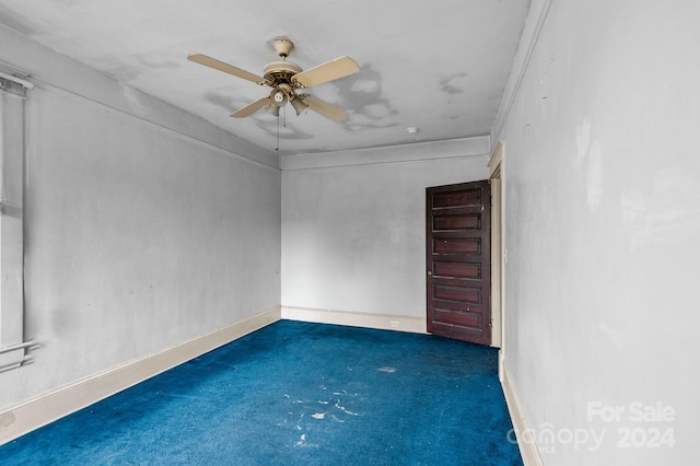 unfurnished room with ceiling fan, ornamental molding, and dark colored carpet