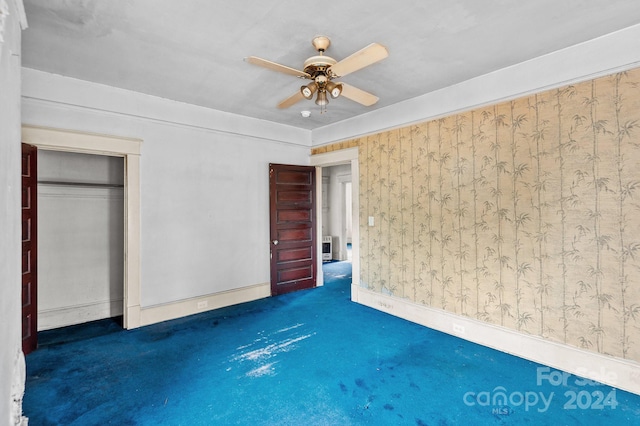 unfurnished bedroom with dark colored carpet, ceiling fan, and a closet