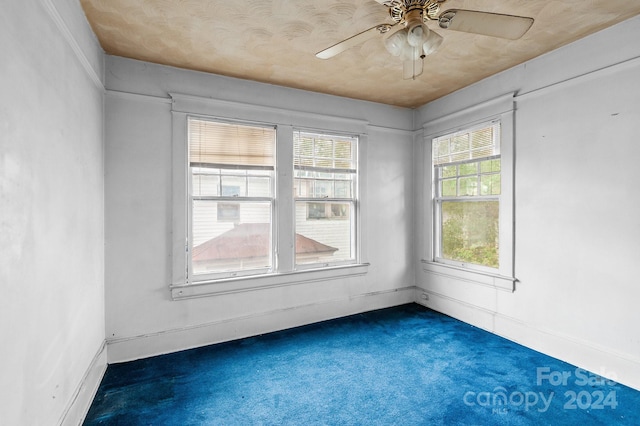 spare room with dark carpet and ceiling fan