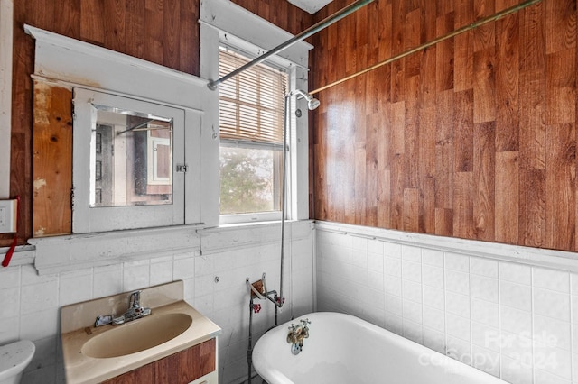 bathroom with vanity, tile walls, toilet, and a washtub